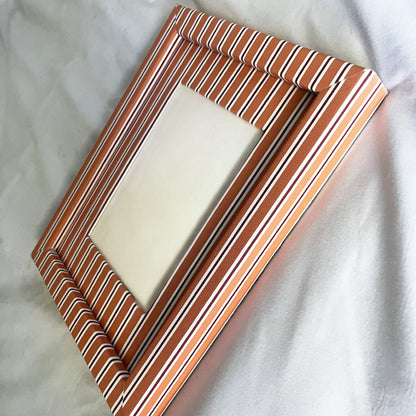 Rectangular picture frame with orange striped design on a white fabric background