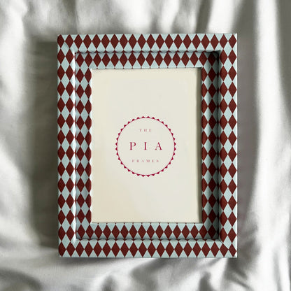 Decorative picture frame with red and blue diamond pattern on a white fabric background