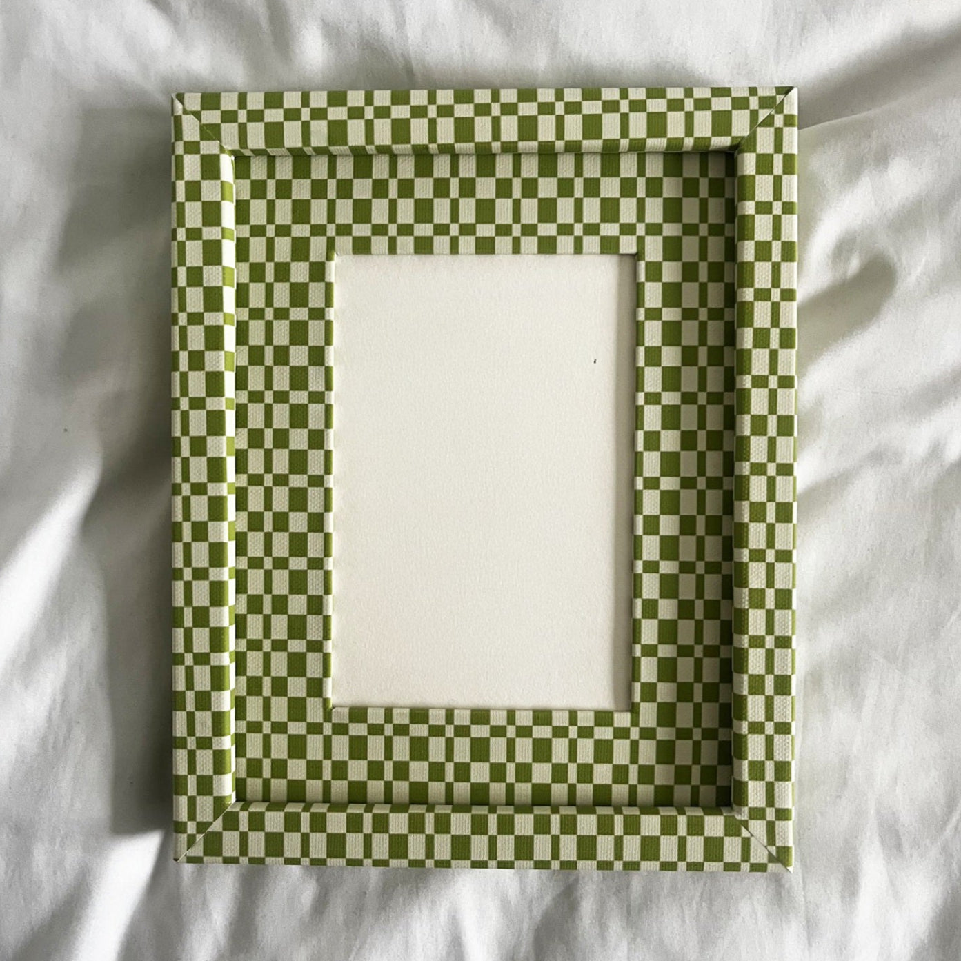 Green checkered frame on a white fabric background
