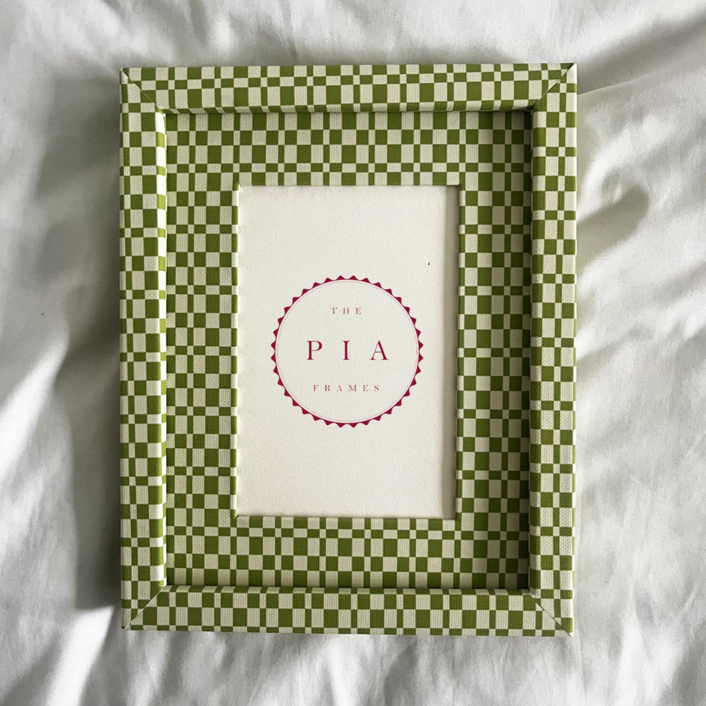 Green checkered frame with a white center on a white fabric background