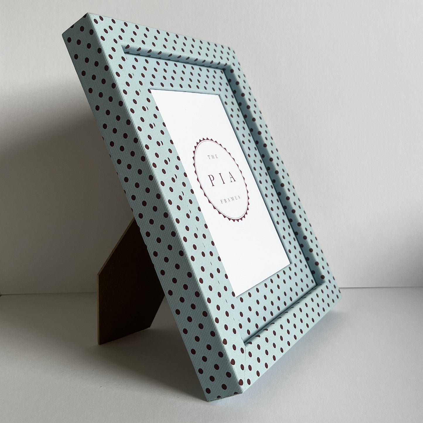 Angled view of handmade blue and burgundy Pembroke polka dot picture frame, showcasing the frame on a stand