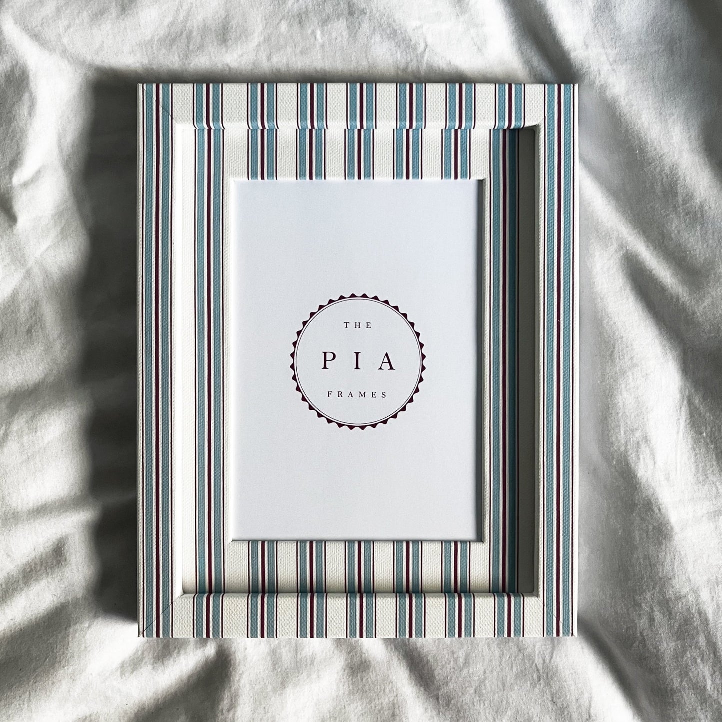 hand made blue and red striped picture frame on a white linen background