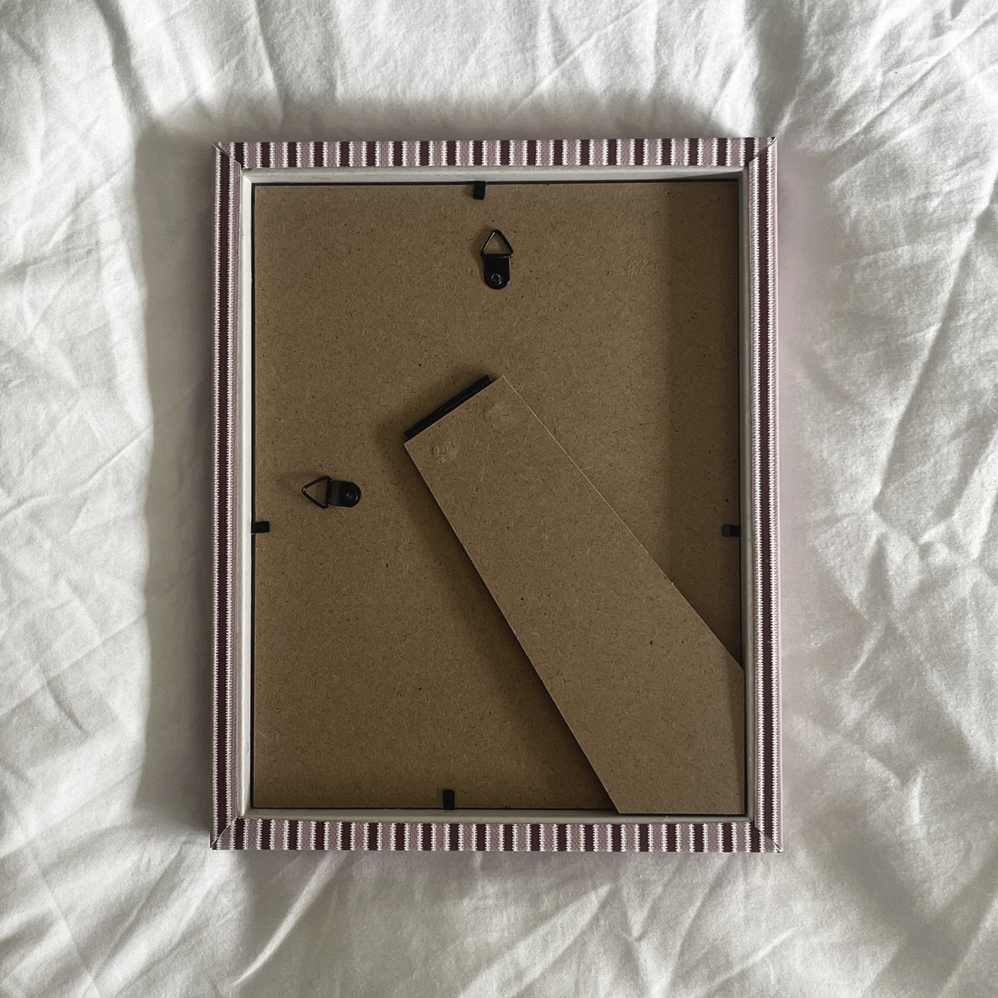 Back of blush and burgundy zigzag picture frame showing wall-mount fittings on white background