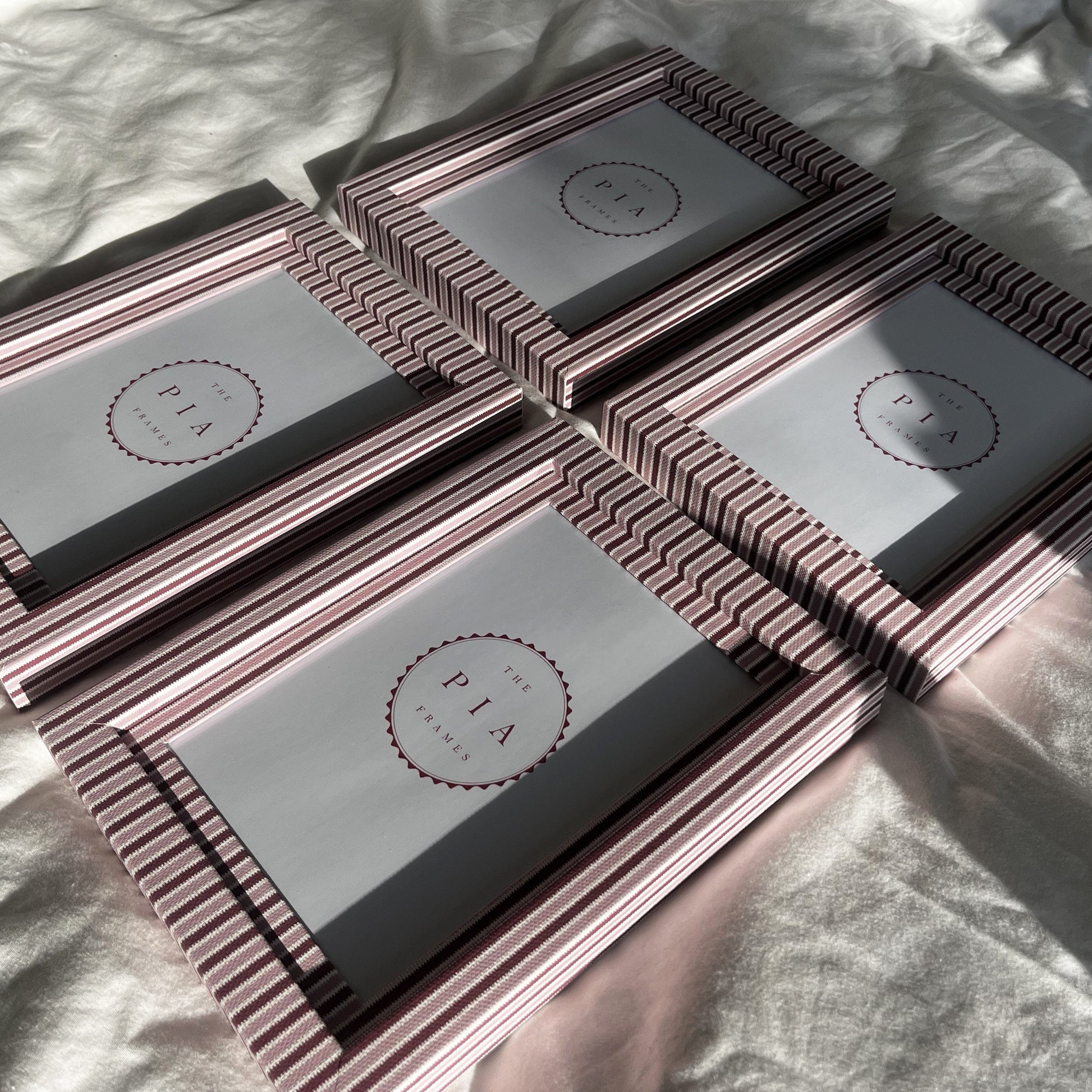 Blush and burgundy zigzag picture frames grouped together on fabric in sunlight, highlighting unique patterns