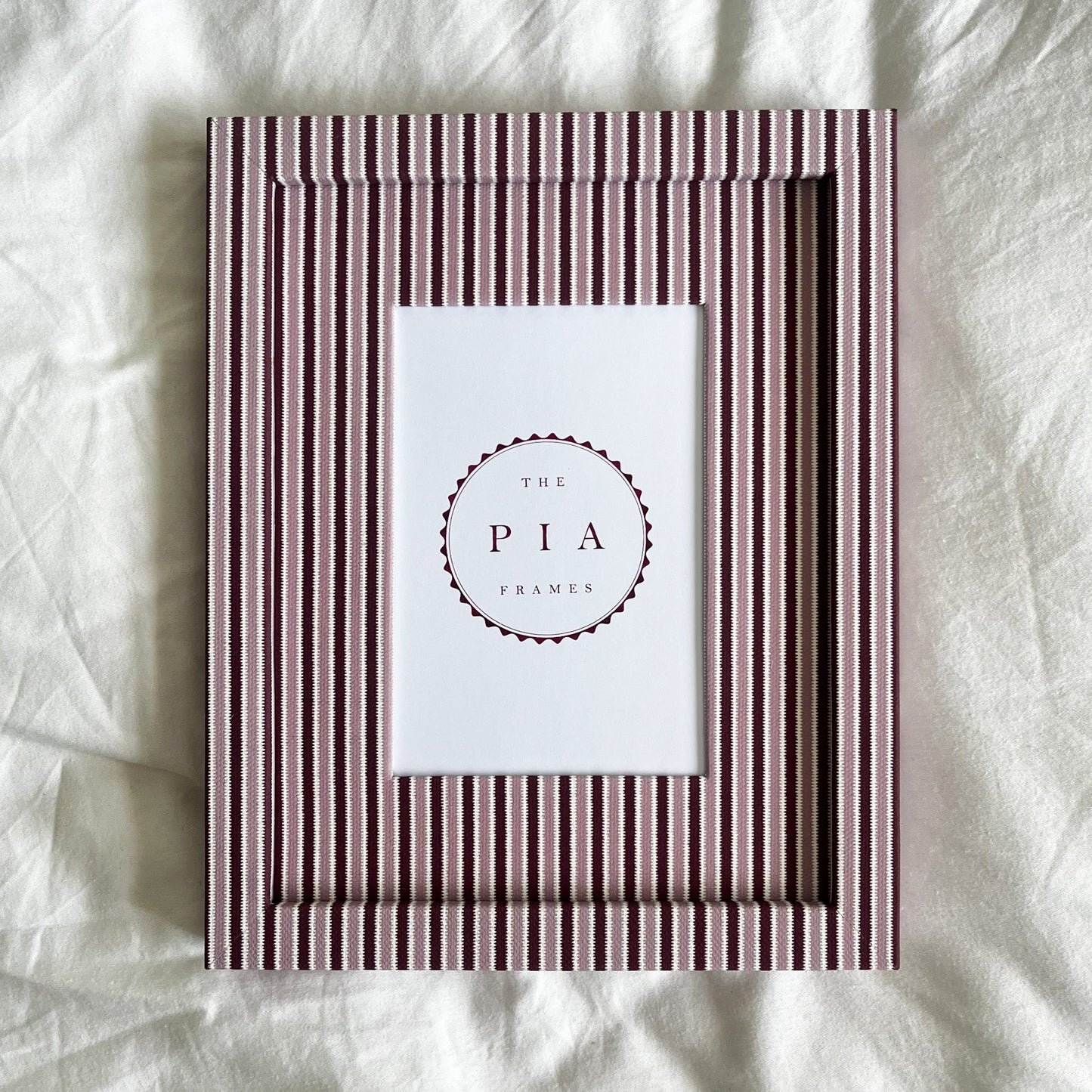 Pink and burgundy striped photo frame on white linen background