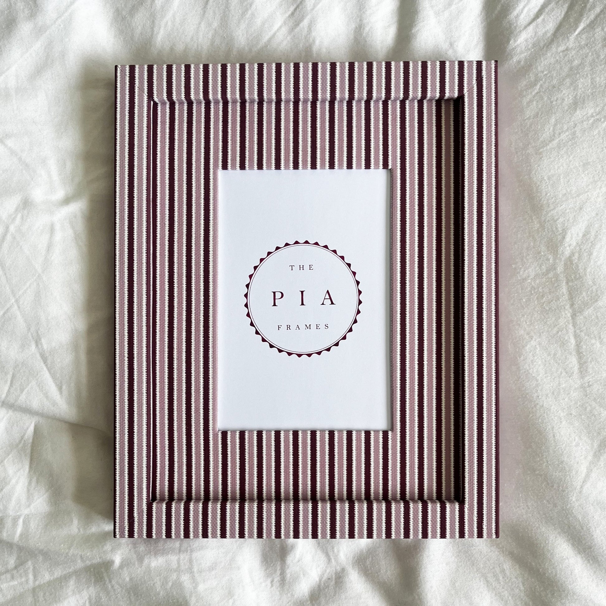 Pink and burgundy striped photo frame on white linen background
