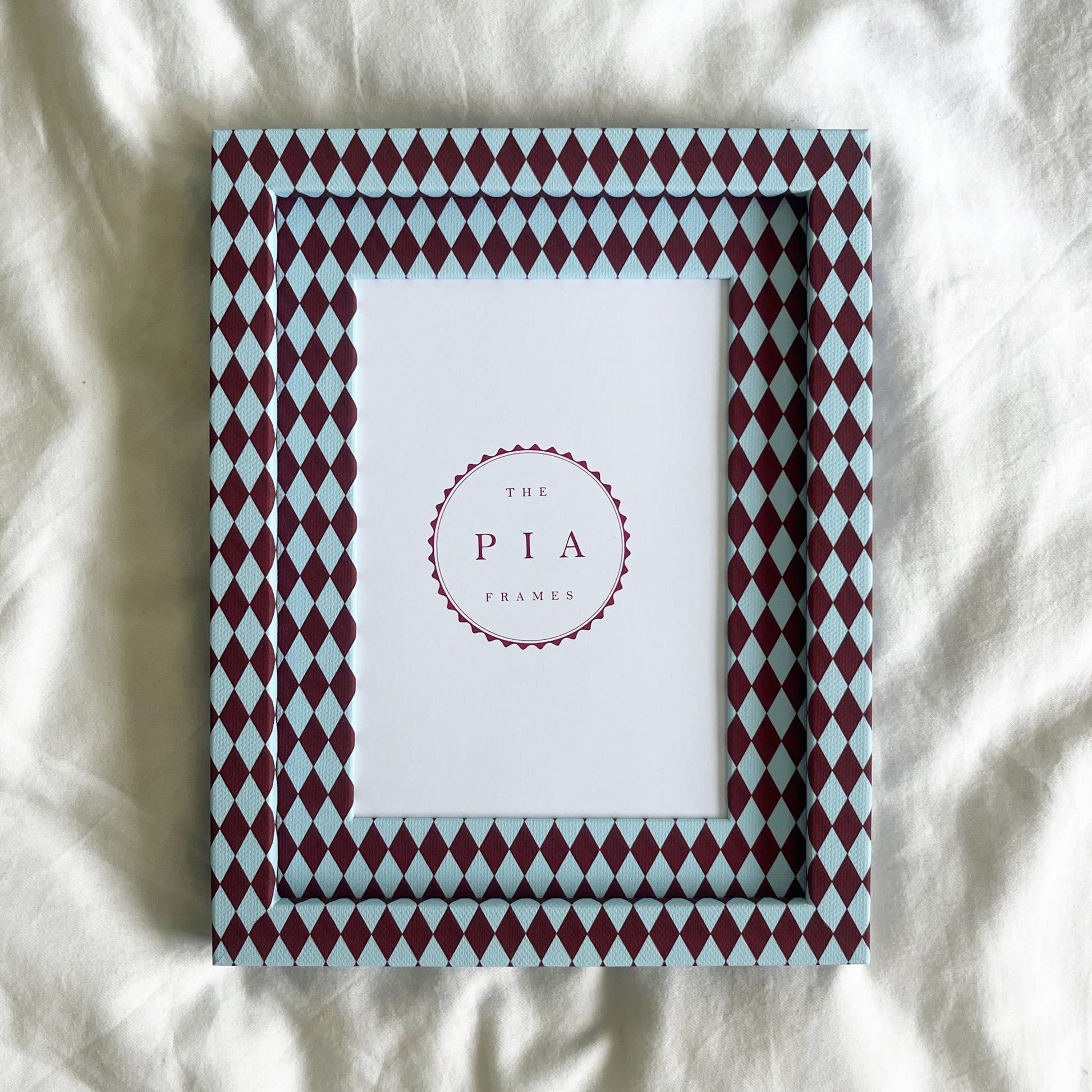 Handmade burgundy and blue harlequin fabric frame, on a white linen fabric