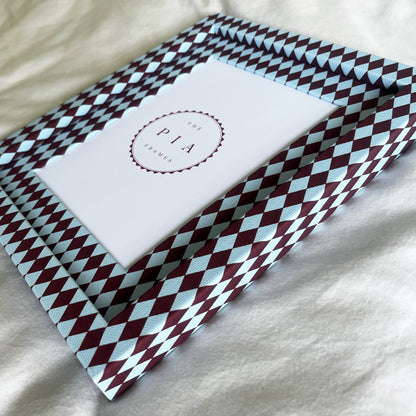 Side view of burgundy and blue harlequin fabric frame, on a white linen fabric, showcasing the depth of the frame