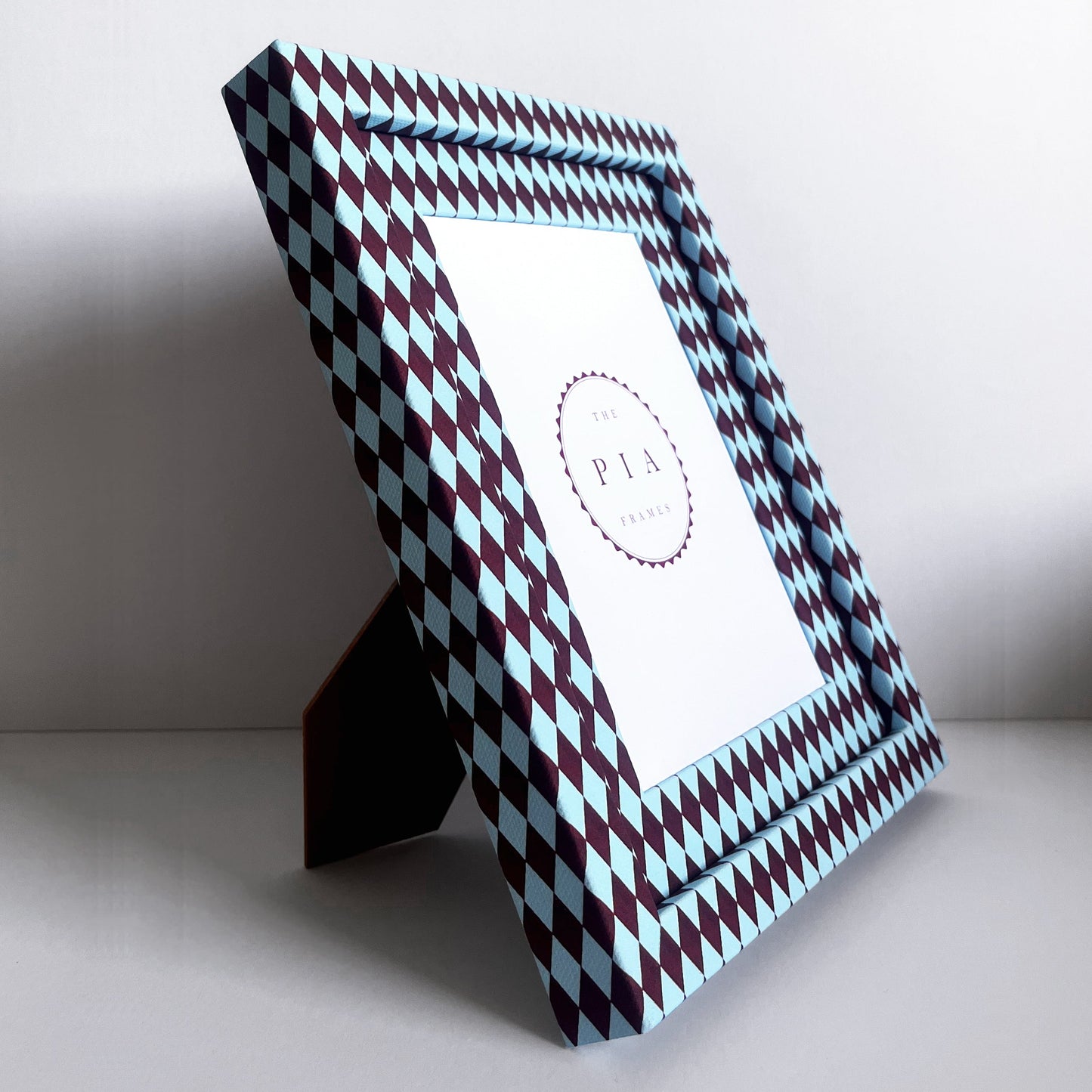 Decorative photo frame with a harlequin fabric frame standing on its stand, in front of a white background