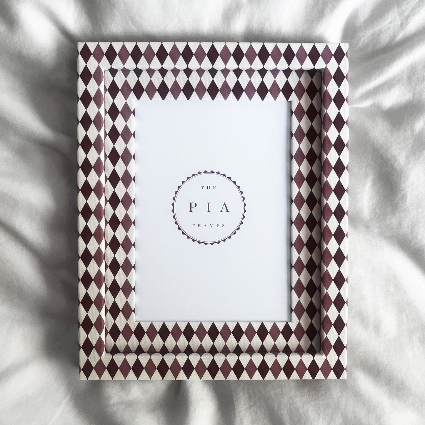Handmade burgundy, blush and white harlequin fabric frame, on a white linen fabric