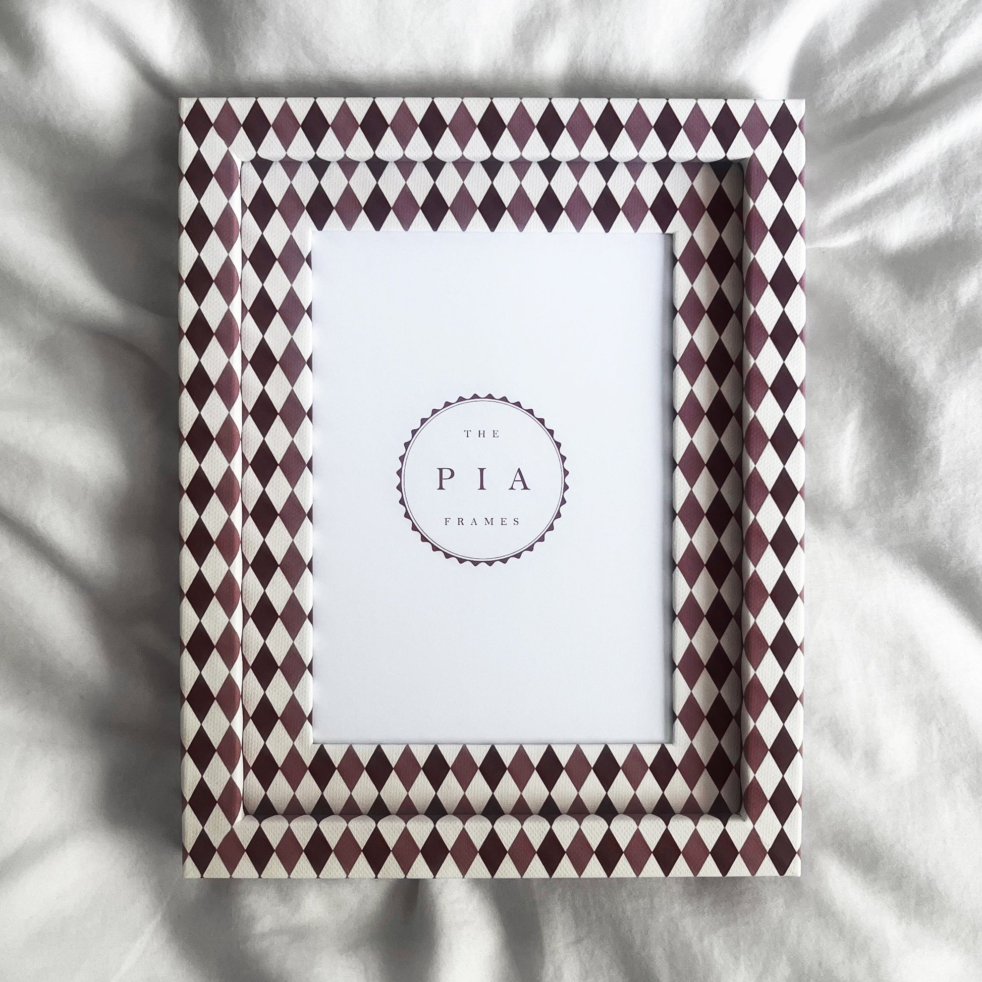 Handmade burgundy, blush and white harlequin fabric frame, on a white linen fabric