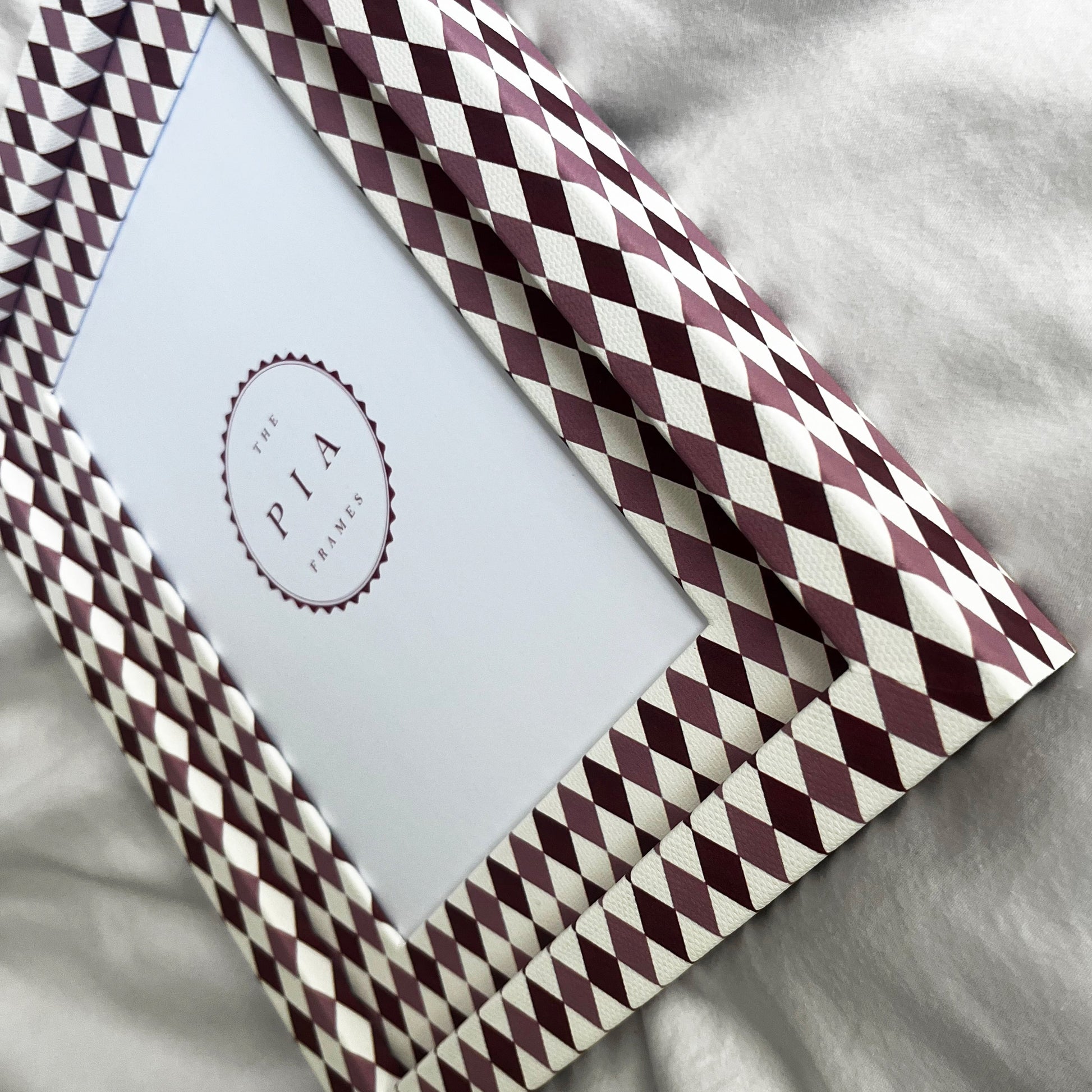 Side view of burgundy, blush and white harlequin fabric frame, on a white linen fabric, showcasing the depth of the frame
