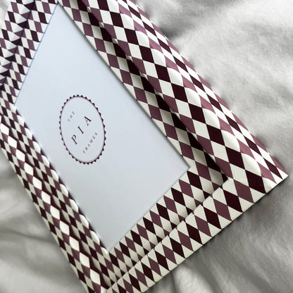 Side view of burgundy, blush and white harlequin fabric frame, on a white linen fabric, showcasing the depth of the frame