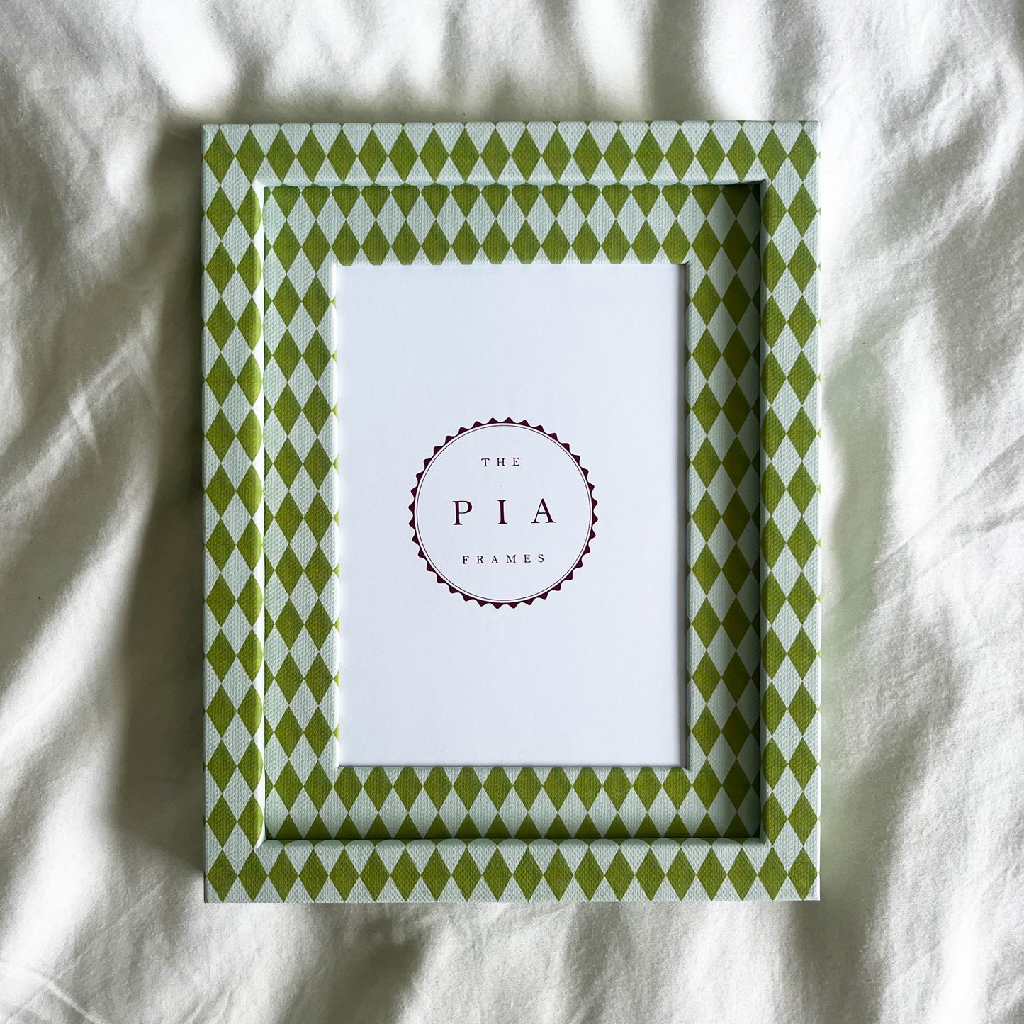 Hand wrapped chartreuse and blue harlequin fabric frame, on a white linen background