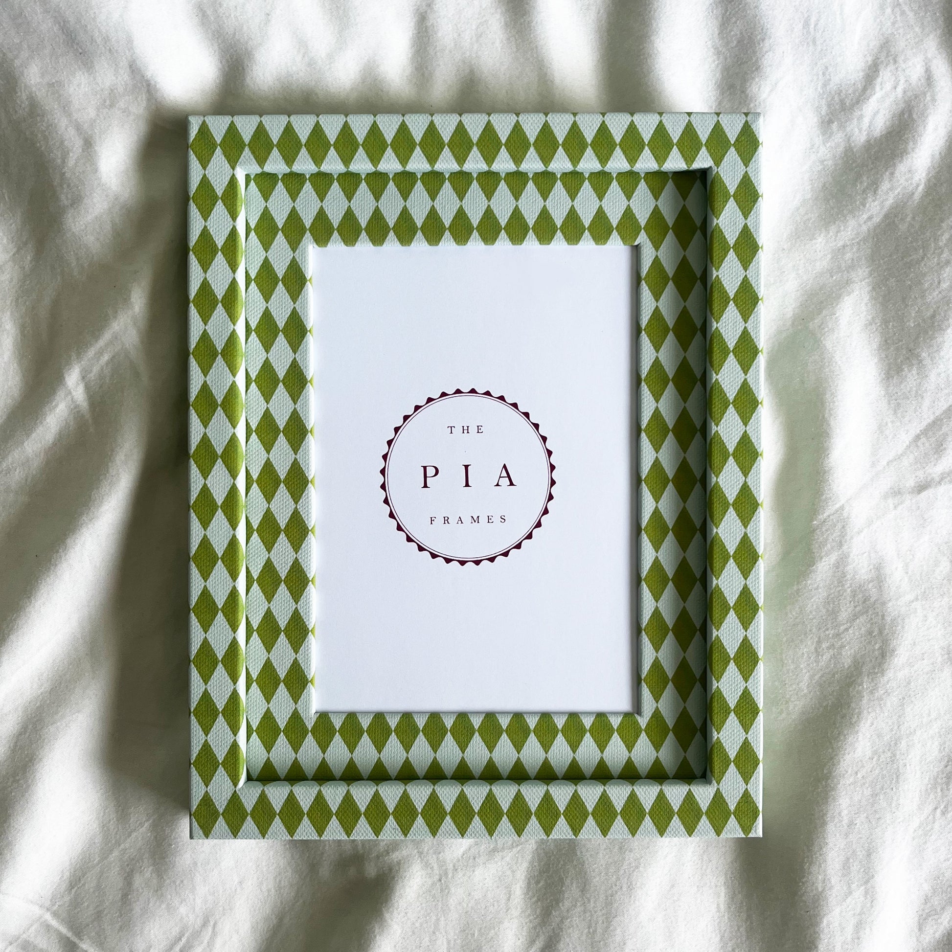 Hand wrapped chartreuse and blue harlequin fabric frame, on a white linen background