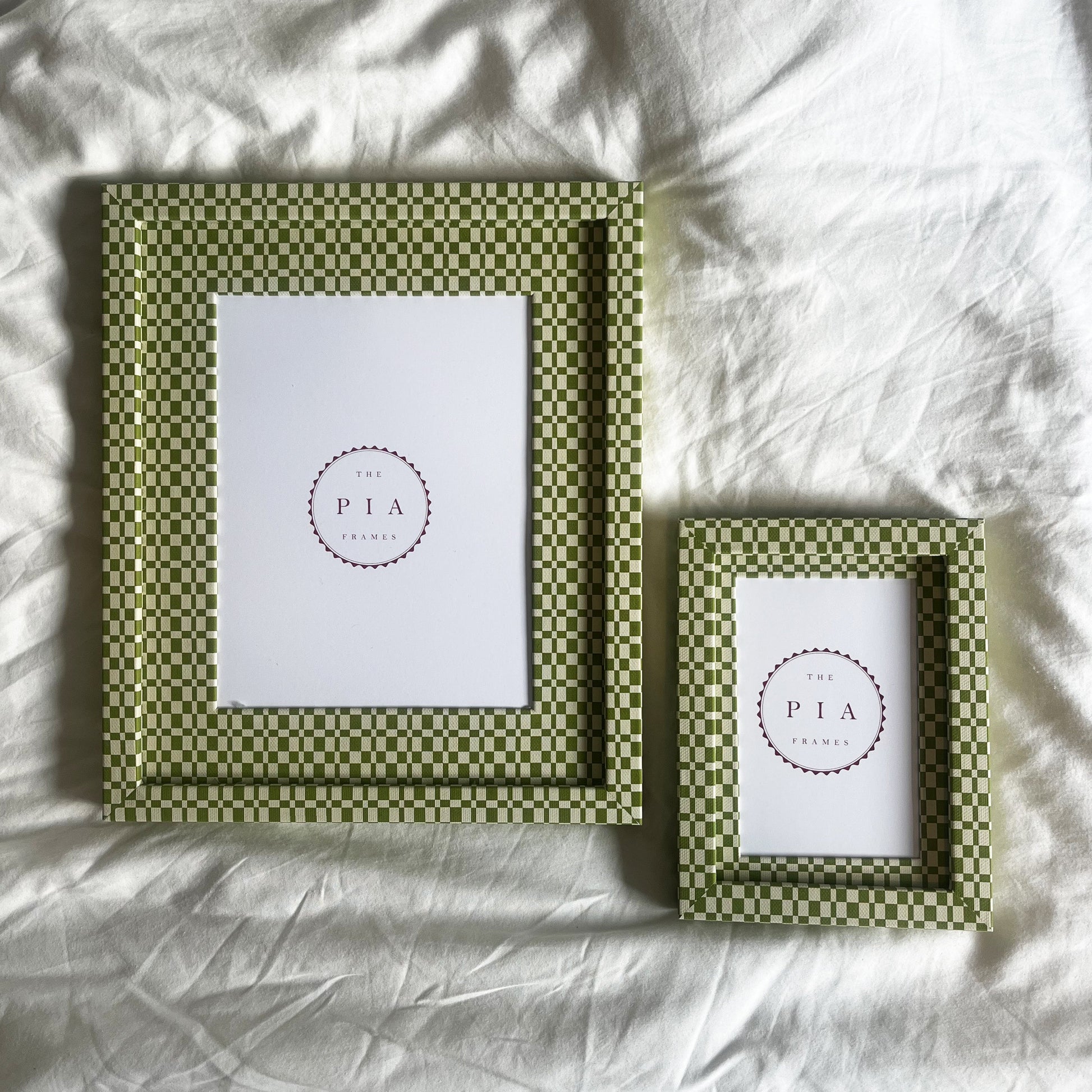 Two green handmade patterned fabric picture frames on a white fabric background