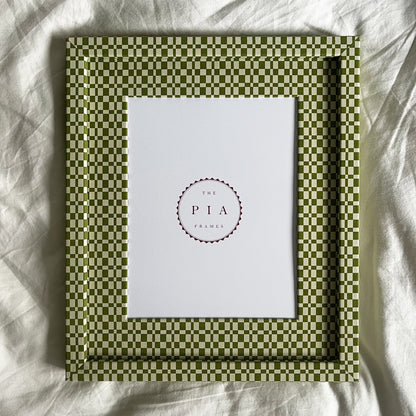 Handmade green checkered frame with a white center on a white fabric background