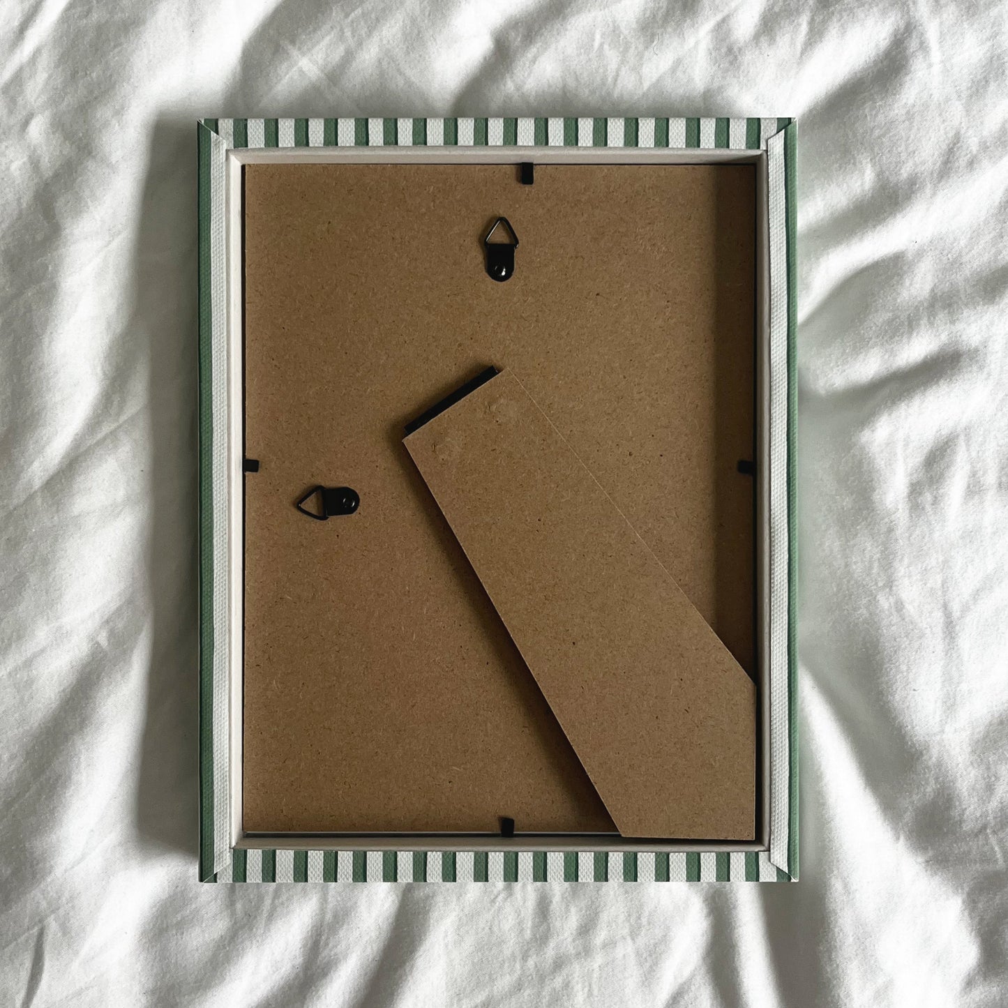 Back view of handmade green vanguard stripe picture frame, showing wall fittings and frame structure