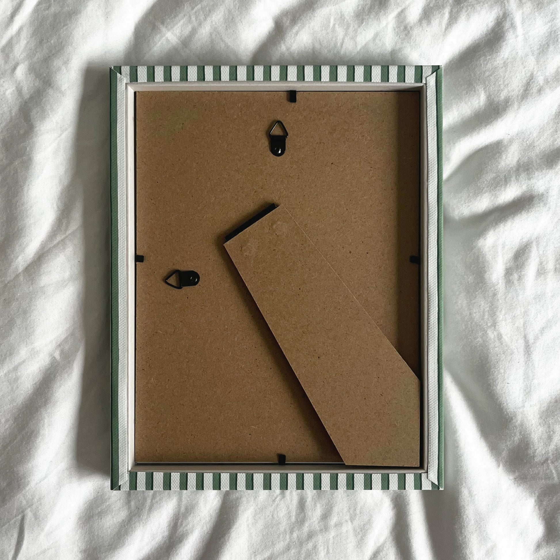 Back view of handmade green vanguard stripe picture frame, showing wall fittings and frame structure