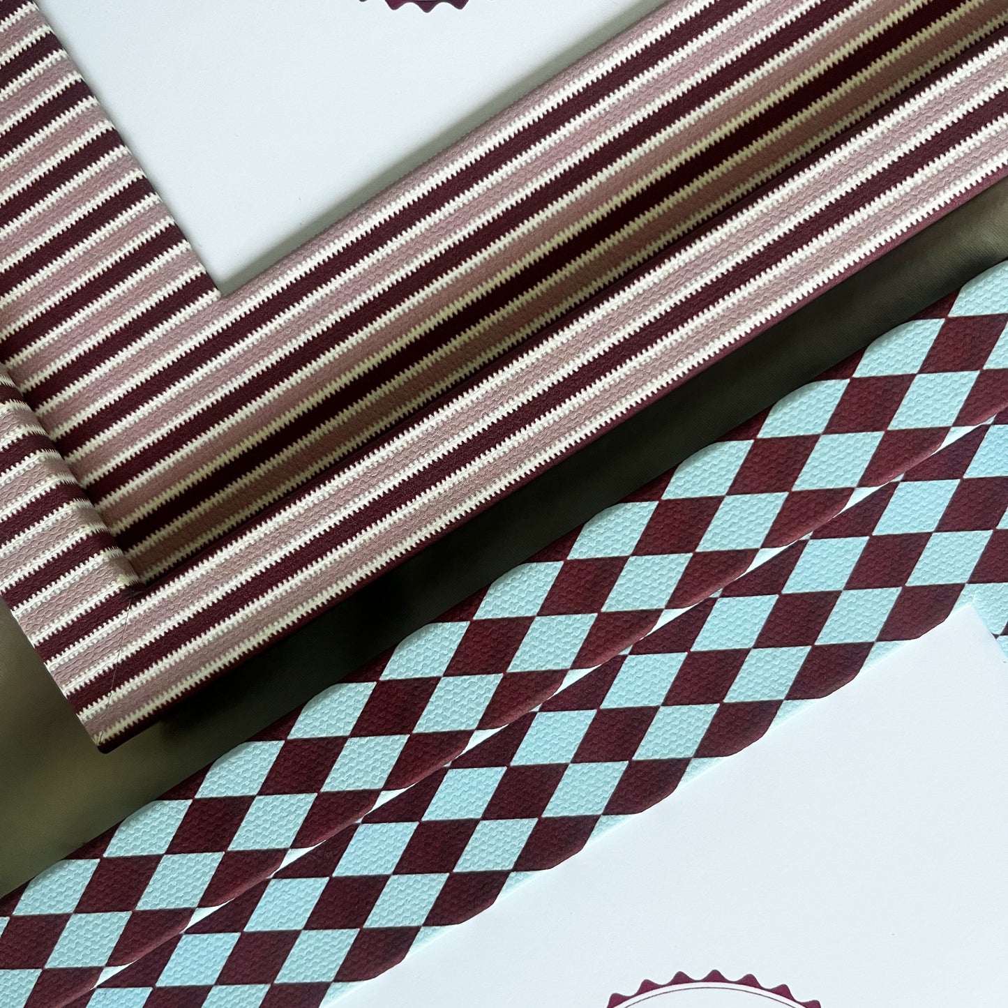 Set of burgundy harlequin and pink striped photo frame arranged on fabric