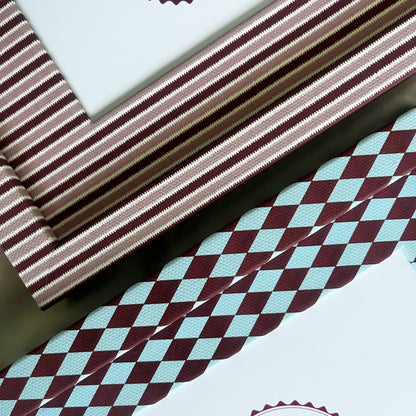 Set of burgundy harlequin and pink striped photo frame arranged on fabric