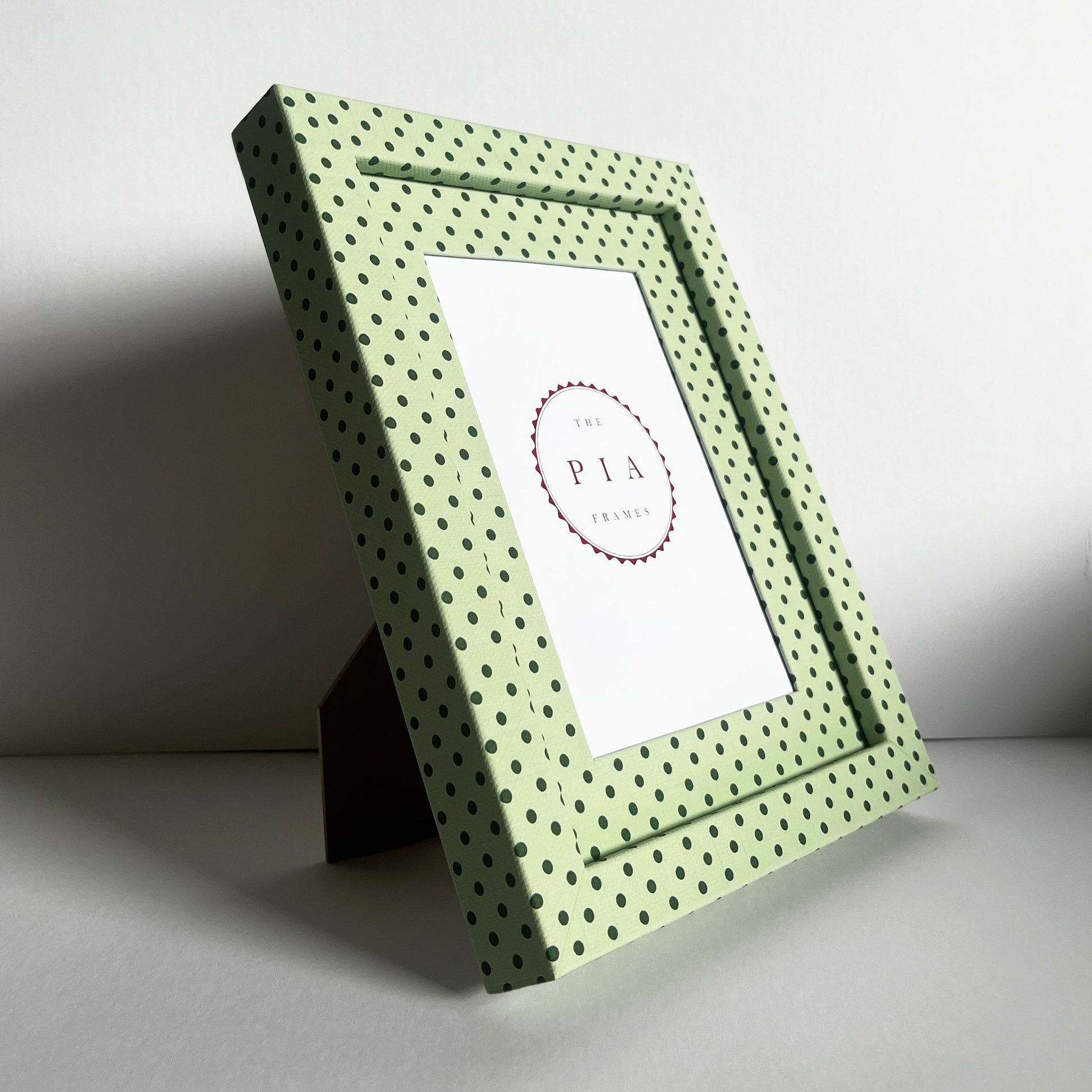 Angled view of handmade mint green and jade Pembroke polka dot picture frame, showcasing the frame on a stand