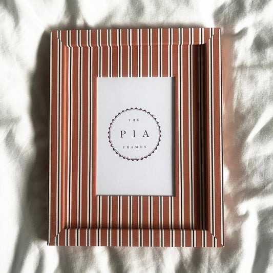 Front view of handmade orange and burgundy stripe picture frame on a neutral background