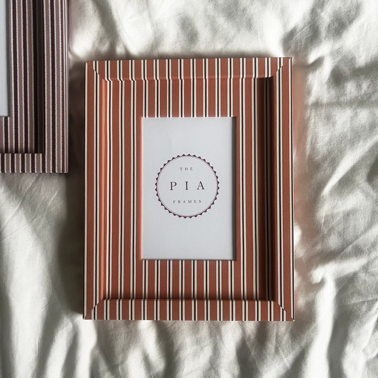 Pairing of handmade orange stripe and blush zigzag picture frames on a neutral background
