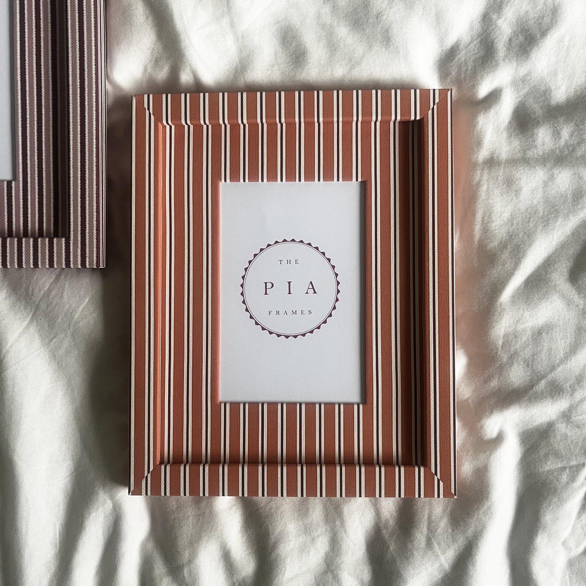 Pairing of handmade orange stripe and blush zigzag picture frames on a neutral background