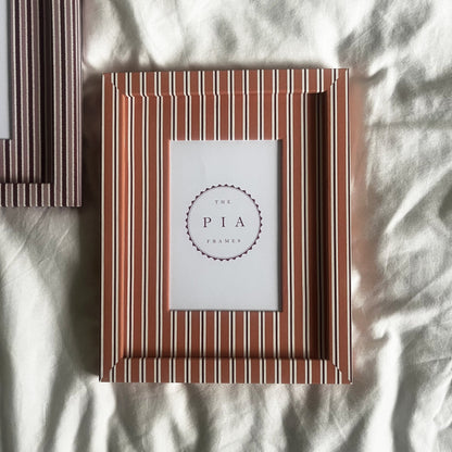 Pairing of handmade orange stripe and blush zigzag picture frames on a neutral background