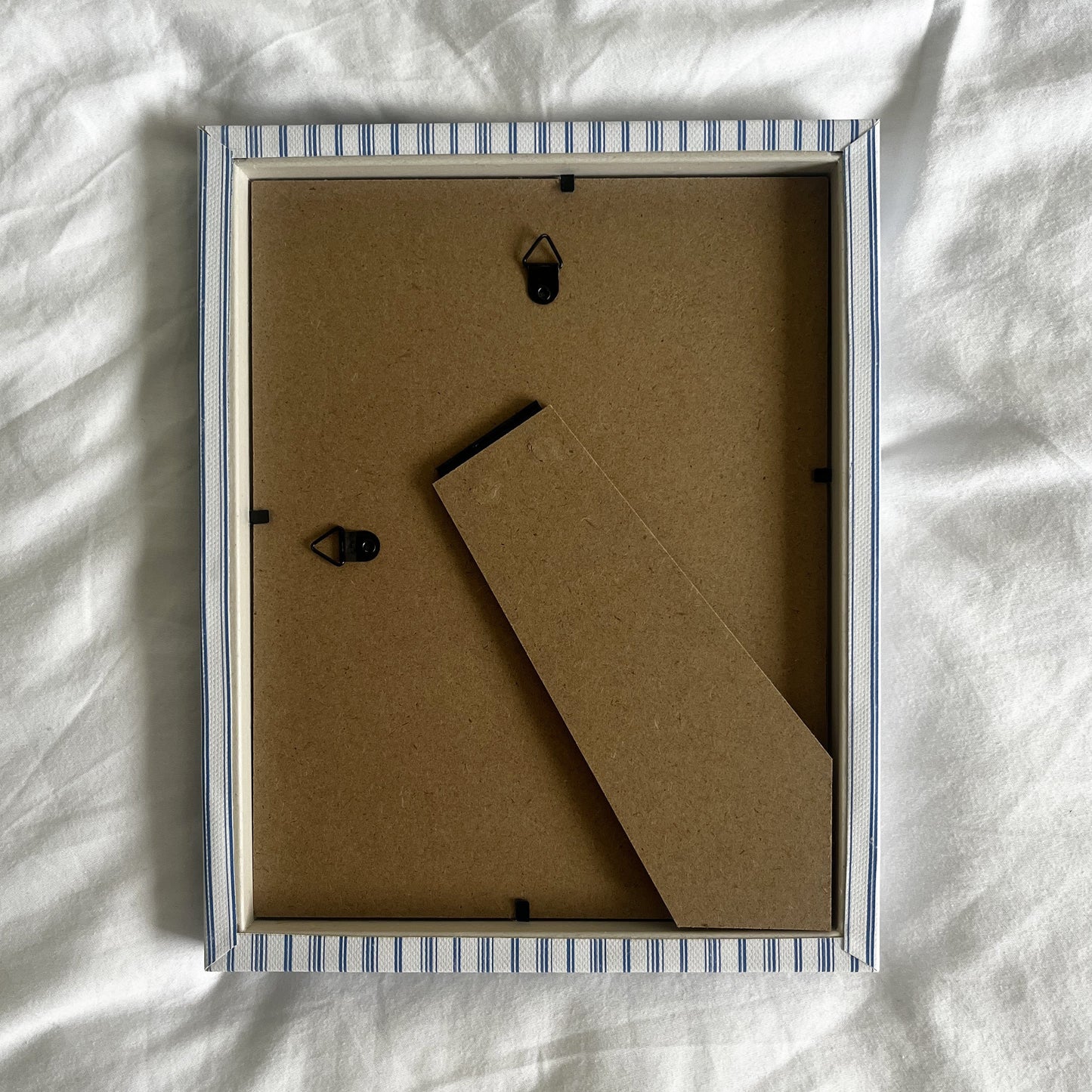 Back view of rustic blue striped picture frame, showing wall fittings and frame structure