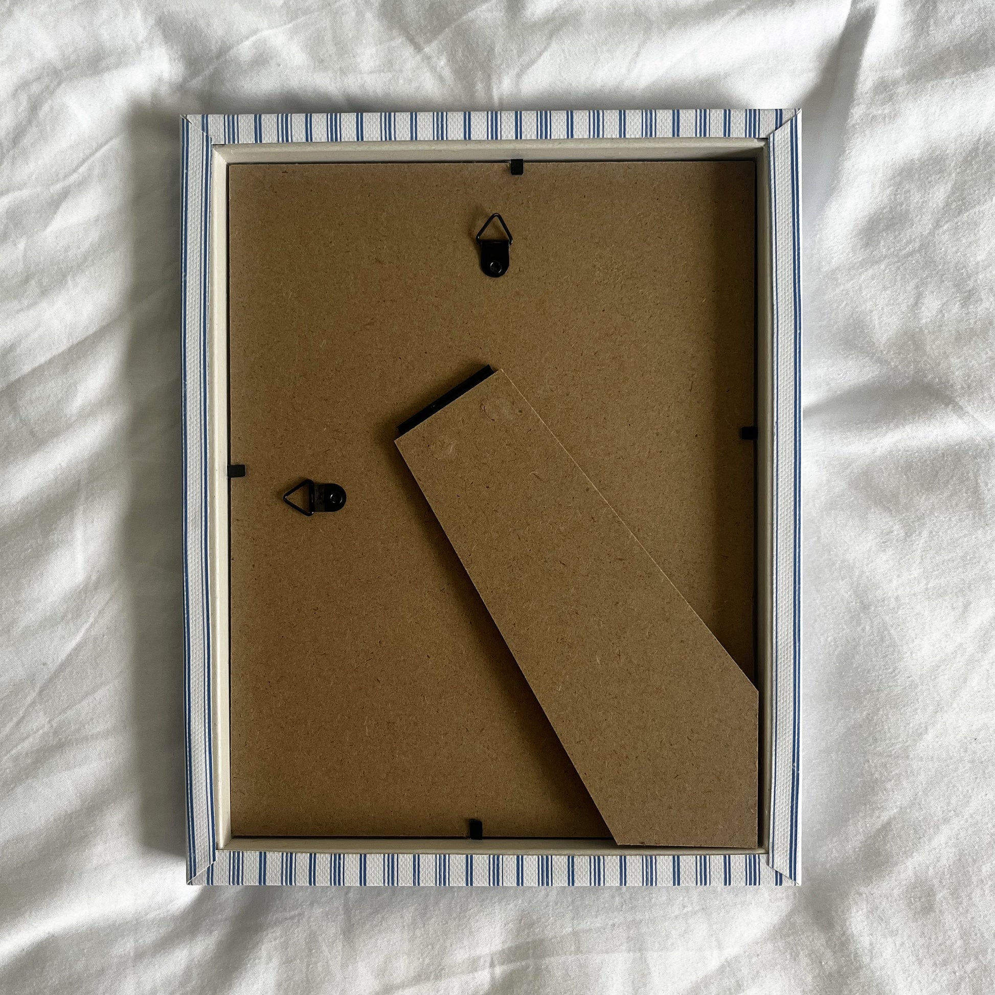 Back view of rustic blue striped picture frame, showing wall fittings and frame structure