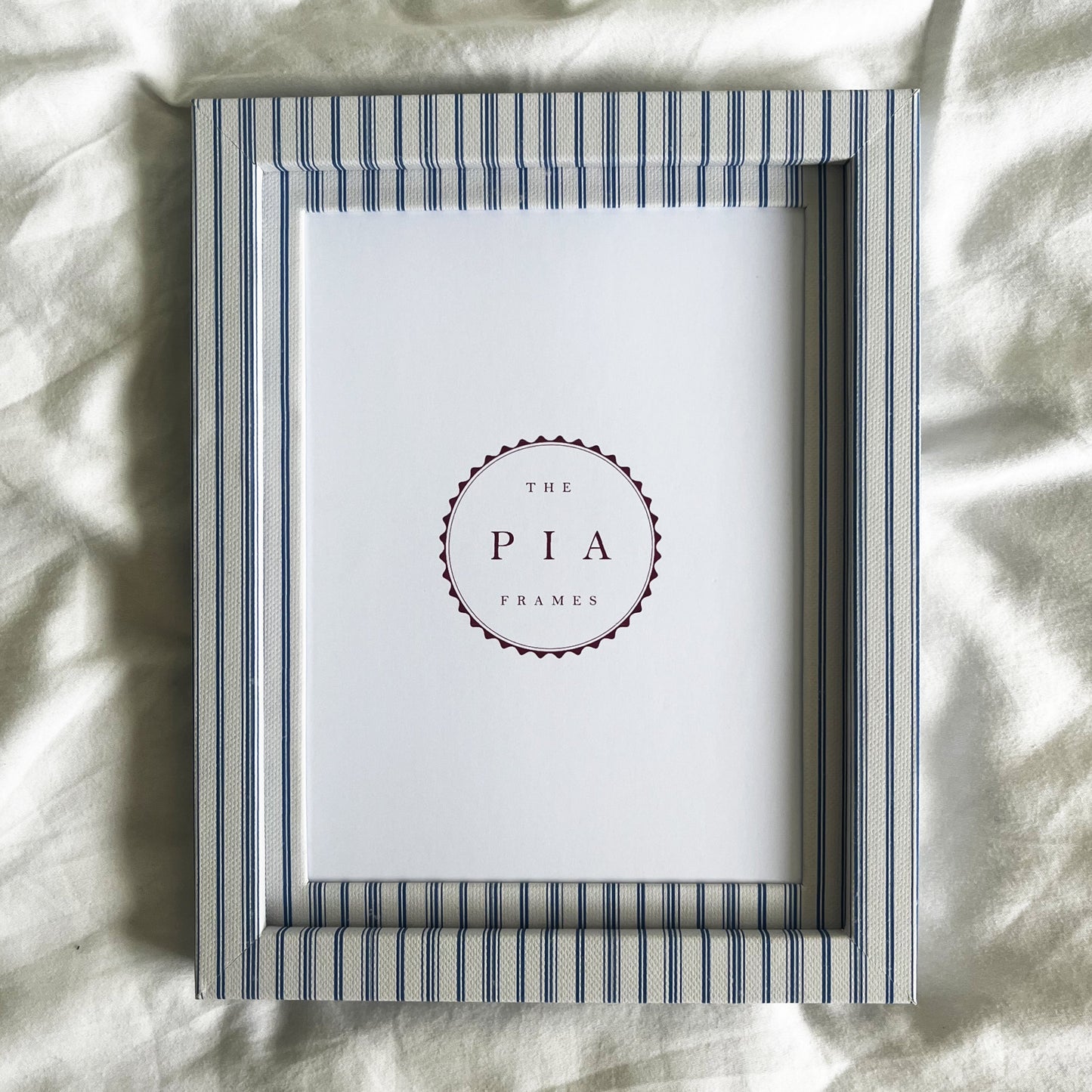 Blue striped picture frame on a white linen background
