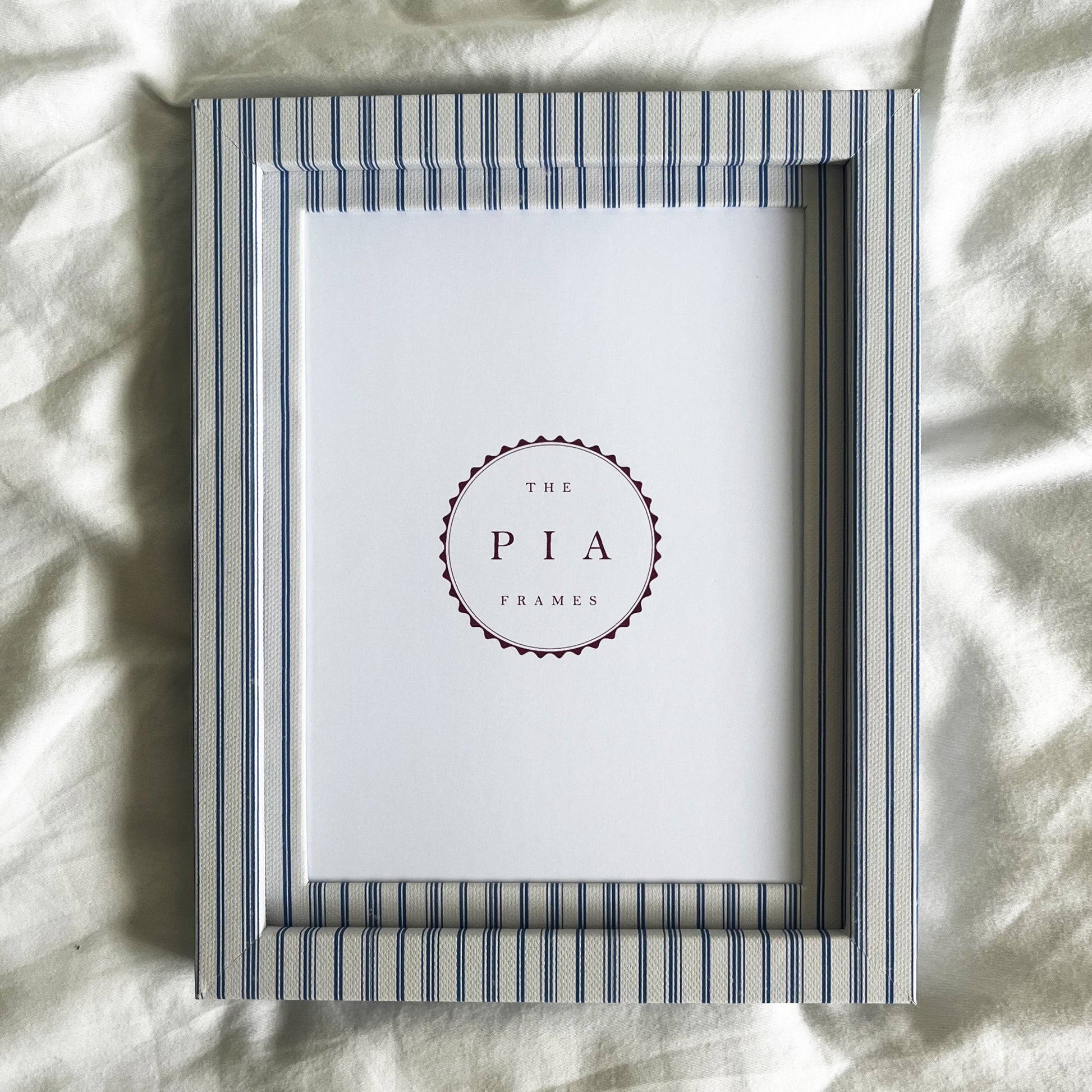 Blue striped picture frame on a white linen background