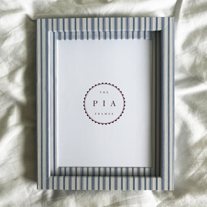 Blue striped picture frame on a white linen background