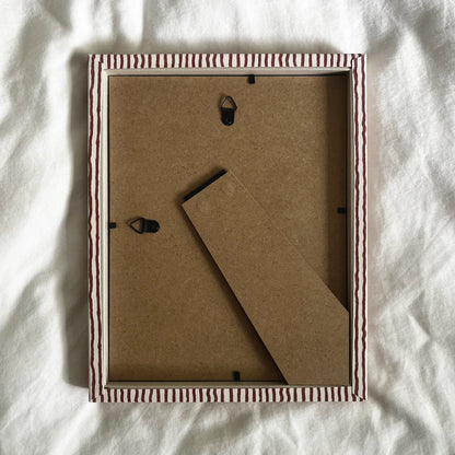 Back view of terracotta and beige striped picture frame, showing wall fittings and frame structure