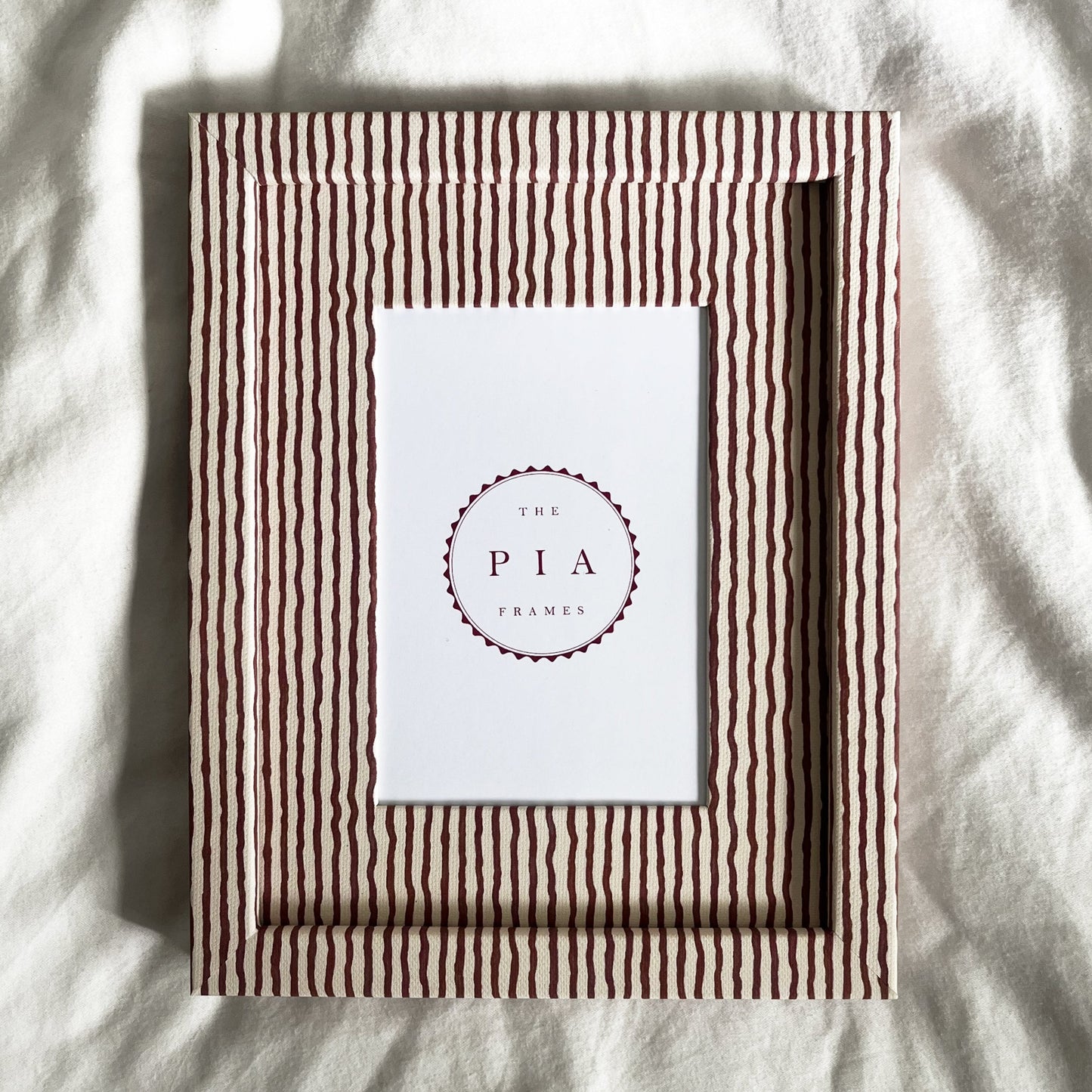 Terracotta and beige striped picture frame on a white linen background