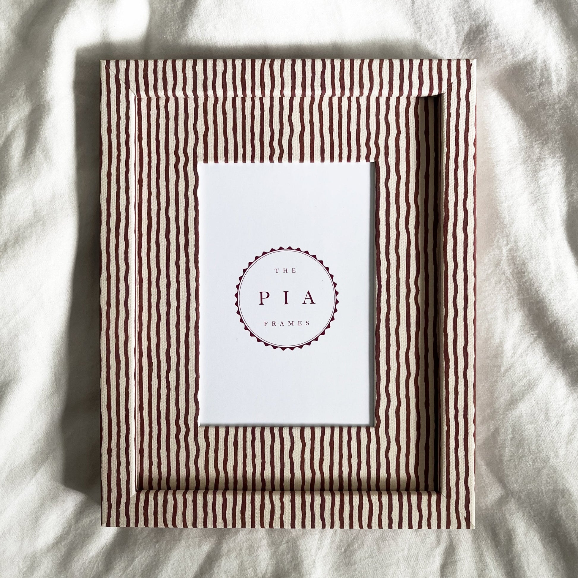 Terracotta and beige striped picture frame on a white linen background