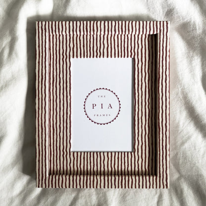 Terracotta and beige striped picture frame on a white linen background