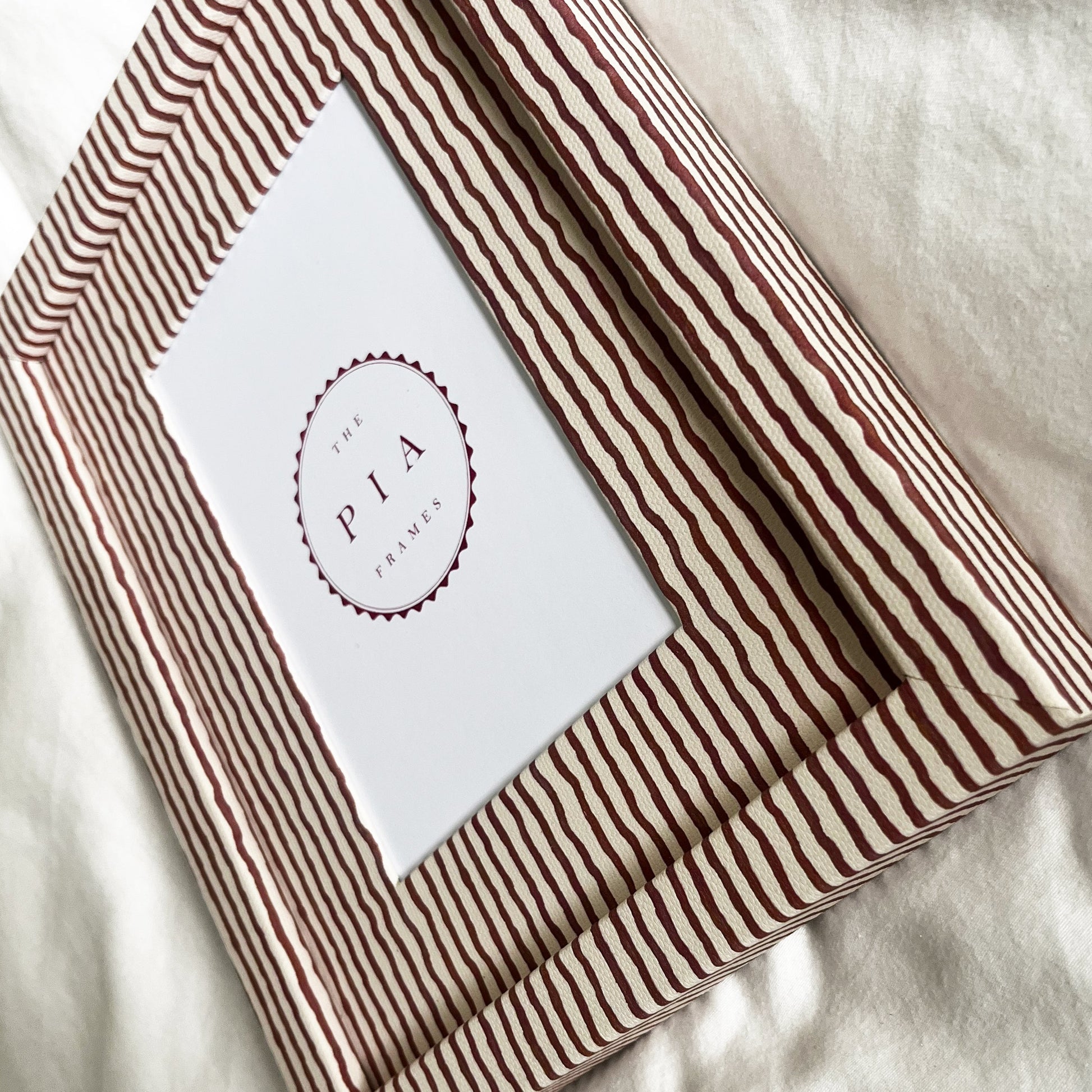 Terracotta striped picture frame on a white linen background