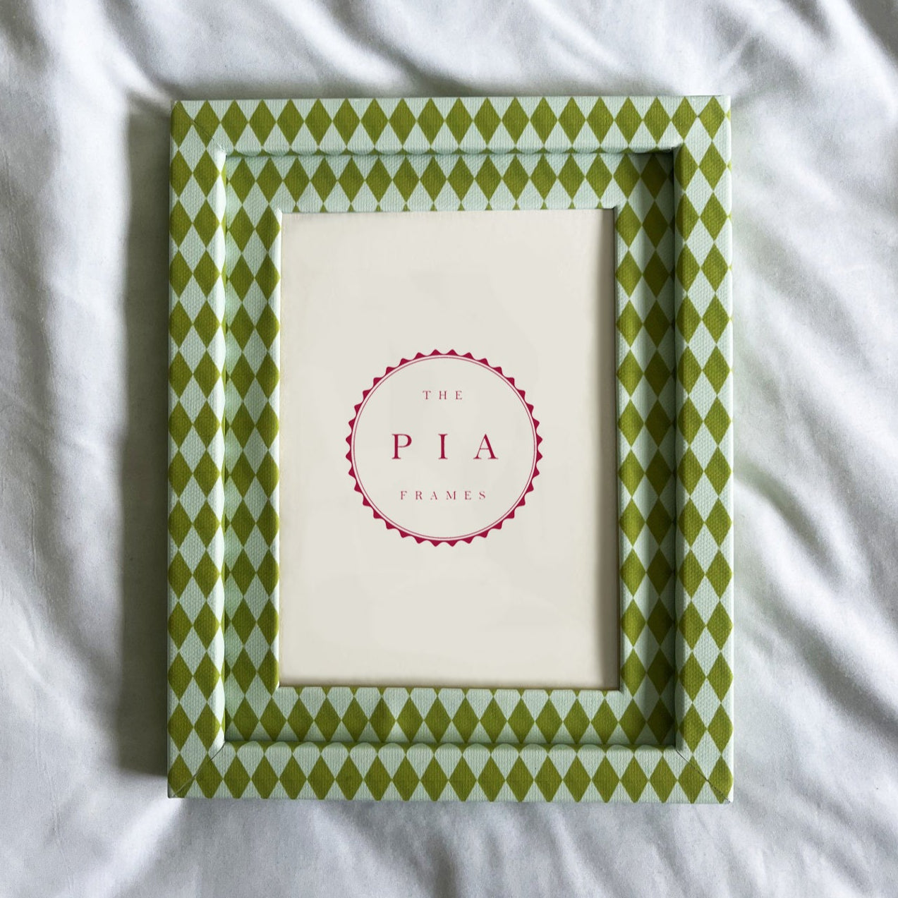 Green patterned frame on a white fabric background